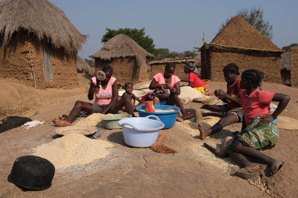 Mulheres na pedra britando milha para fazer farinha de milho para cozinharem a Fuba, prato que serve de base á alimentação deste povo